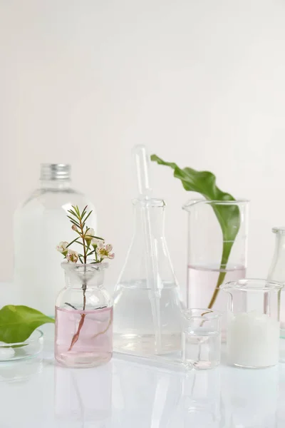 天然成分と白色テーブル上の有機化粧品のための研究室のガラス製品 — ストック写真