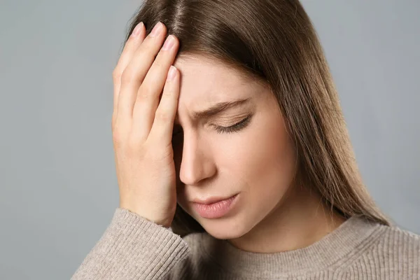 Gri Arka Planda Migren Ağrısı Çeken Genç Bir Kadın — Stok fotoğraf