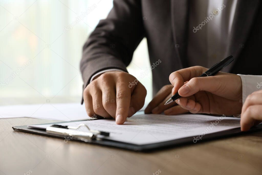 Businesspeople working with document at table indoors, closeup