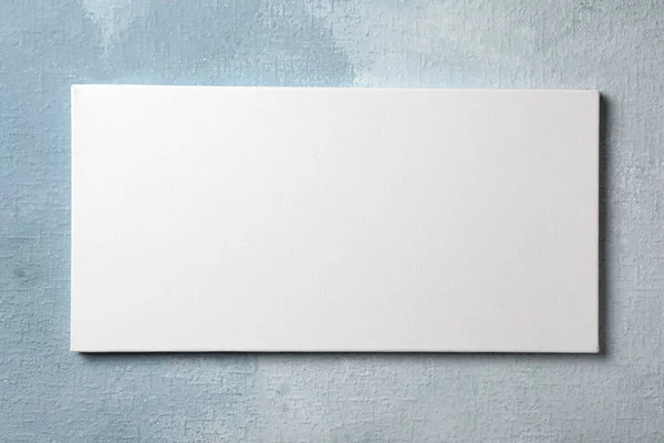 Blank canvas hanging on white wall, space for text Stock Photo
