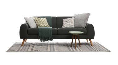 Beyaz arka planda yastıklı, battaniyeli ve masalı rahat gri bir kanepe. Oturma odası için mobilyalar.