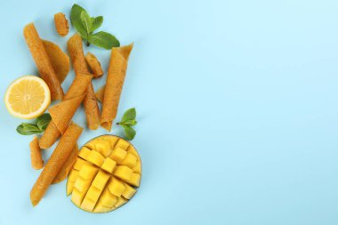 Lezzetli meyve dürümleri, mango, nane ve limon açık mavi arka planda, düz yatak. Metin için boşluk