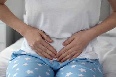 Karın ağrısı çeken bir kadın evinde yatıyor, yakın plan.