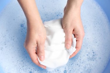 Beyaz elbiseleri köpükle yıkayan kadının üst görüntüsü, yakın plan.