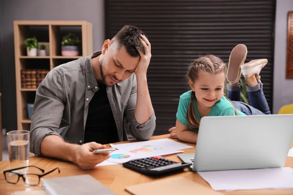 Overwhelmed man combining parenting and work at home