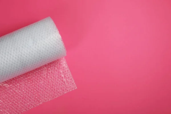 Bubble wrap roll on pink background, top view. Space for text