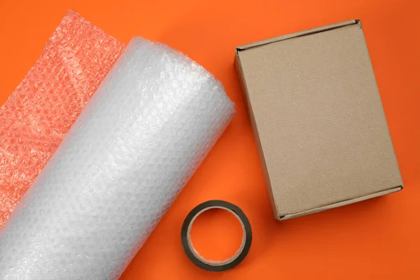 Rollo Papel Burbuja Caja Cartón Cinta Adhesiva Sobre Fondo Naranja — Foto de Stock