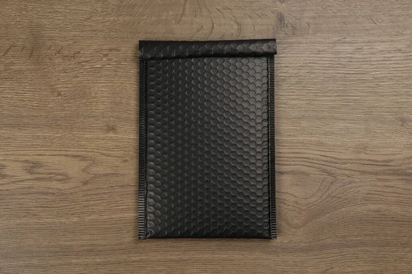 Μαύρο Παραγεμισμένο Φάκελο Φυσαλίδα Περιτύλιγμα Ξύλινο Φόντο Πάνω Όψη — Φωτογραφία Αρχείου