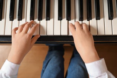 Küçük çocuk piyano çalıyor, yukarıdan. Müzik dersi