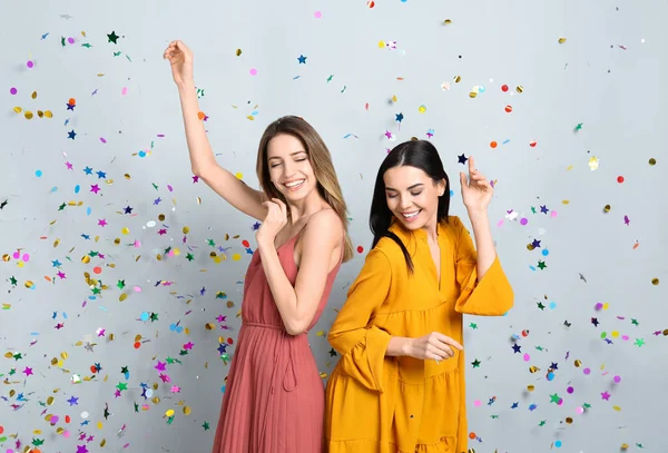 Mulheres Felizes Confetes Caindo Fundo Cinza Claro — Fotografia de Stock