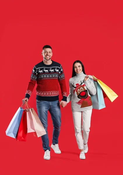Glada Par Med Papperspåsar Röd Bakgrund Julhandel — Stockfoto