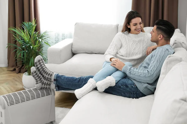 Feliz Pareja Sentada Sofá Cerca Del Calentador Eléctrico Casa — Foto de Stock