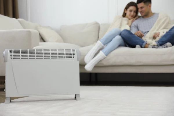 Electric heater and couple on sofa at home