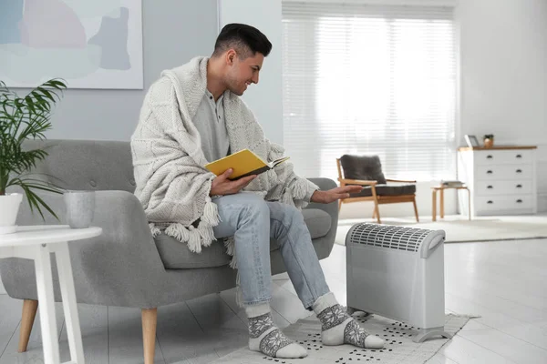 Homme Heureux Avec Livre Assis Sur Canapé Près Chauffage Électrique — Photo