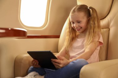 Uçakta tablet kullanan tatlı küçük kız.