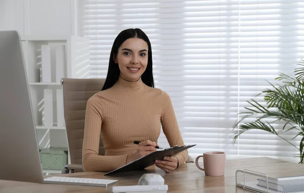 Secretary working at wooden table in office