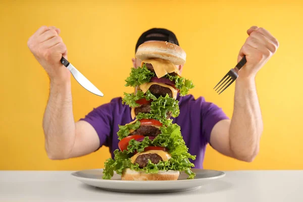 Uomo Affamato Con Posate Hamburger Enorme Tavolo Bianco Sfondo Giallo — Foto Stock