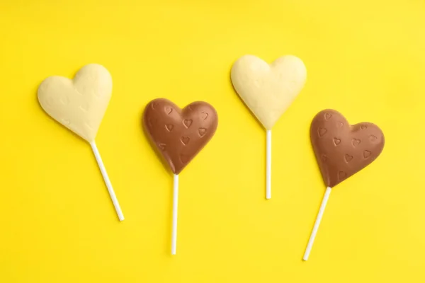Farklı Çikolata Kalp Şekilli Lolipoplar Sarı Arka Planda Düz Yerde — Stok fotoğraf