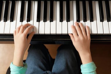 Küçük çocuk piyano çalıyor, yukarıdan. Müzik dersi