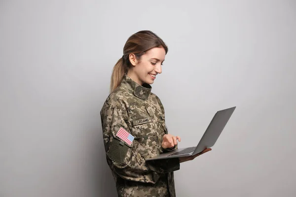 ライトグレーの背景にノートパソコンを持つ女性士官候補生 軍事教育 — ストック写真
