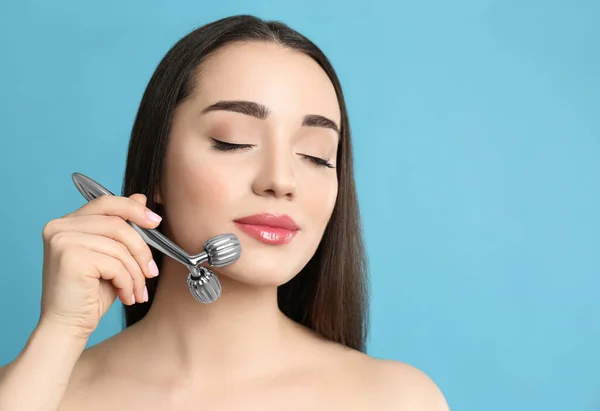 Mujer Usando Rodillo Facial Metal Sobre Fondo Gris Claro Espacio —  Fotos de Stock