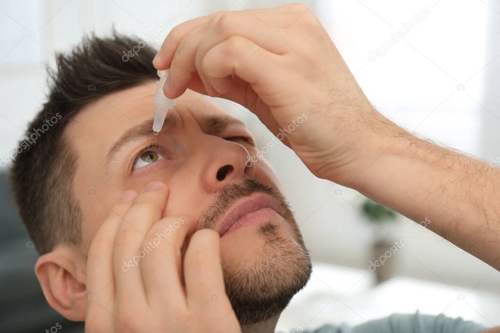 Man using drops for eyes at home