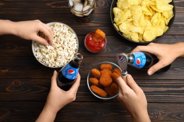 MYKOLAIV, UKRAINE - 16 Şubat 2021: Pepsi ve aperatiflerle ahşap masa, üst manzara