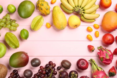 Farklı egzotik meyvelerin çerçevesi pembe ahşap masada, düz yerde. Metin için boşluk