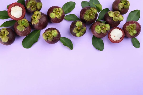 薄紫色の背景に緑色の葉を持つ新鮮な熟したマンゴスチンの果物 フラットレイ テキストのスペース — ストック写真