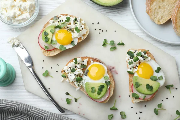 Läckra Smörgåsar Med Ägg Ost Avokado Och Mikrogröna Vitt Träbord — Stockfoto