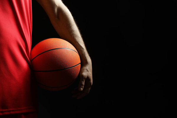 Basketball player with ball on black background, closeup. Space for text