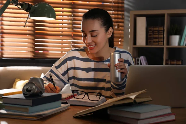 Young woman with energy drink studying at home