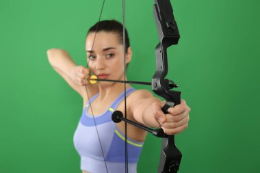 Yeşil arka planda okçuluk yapan genç kadın, yaylara odaklan.
