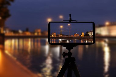 Gece vakti güzel şehir manzarasının fotoğrafını çekiyoruz. Akıllı telefon tripoda monte edilmiş.