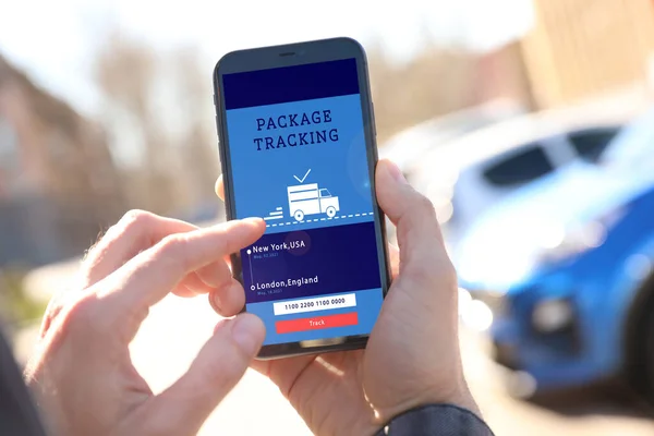 Man tracking parcel via smartphone outdoors, closeup