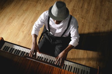 African-American man playing piano indoors, above view. Talented musician clipart