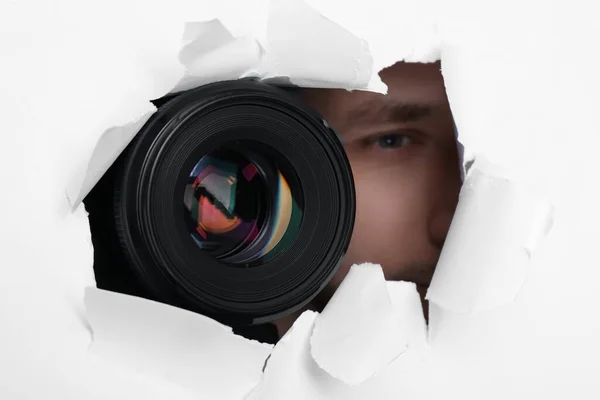 隠し男とカメラスパイスルー引き裂かれた穴に白い紙 クローズアップ — ストック写真