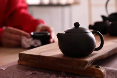 Traditional tea ceremony, focus on teapot. Guest holding cup at table, closeup clipart