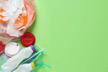 Yeşil arka planda farklı plastik eşyalar yığını. Metin için boşluk