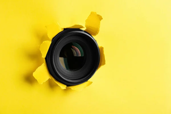 黄色い紙に穴を通って隠しカメラレンズ — ストック写真