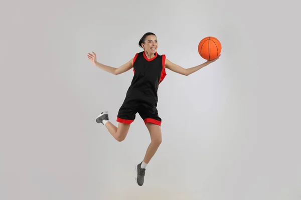 グレーの背景でバスケットボールをしているプロのスポーツ女性 — ストック写真