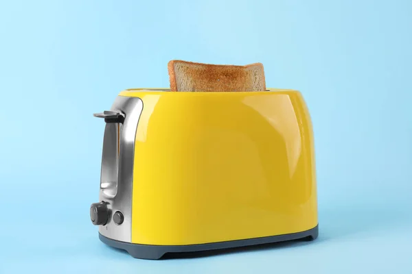 Moderne Broodrooster Met Sneetje Brood Lichtblauwe Achtergrond — Stockfoto