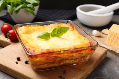 Gri masada pişirme kabında pişirilmiş lezzetli lazanya, yakın plan.