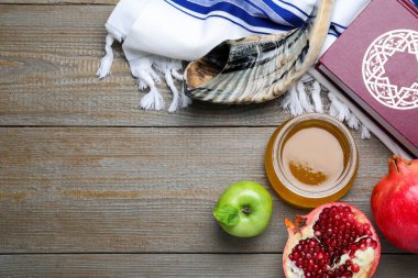 Honey, pomegranate, apples, shofar and Torah on wooden table, flat lay with space for text. Rosh Hashana holiday clipart