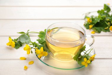 Beyaz ahşap masada cam bardak aromalı selanik çayı ve çiçekler.