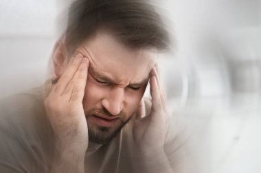 Young man suffering from migraine at home, closeup clipart