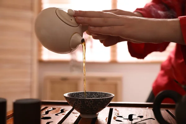 在传统的酒会上 主人在餐桌前把新鲜煮好的茶倒入杯中 进行特写 — 图库照片