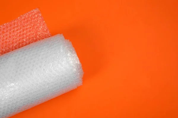 Bubble wrap roll on orange background, top view. Space for text
