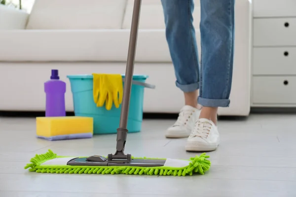 Woman washing floor with mop in living room, closeup