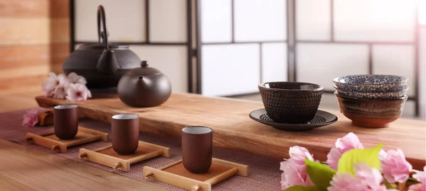 木製のテーブルの上に伝統的な茶道や桜の花のための美しいセット バナーデザイン — ストック写真